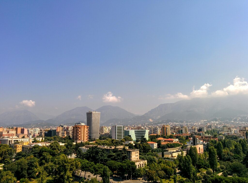 Aerial view of Tirana, Albania's capital, with mountain backdrop and clear skies.