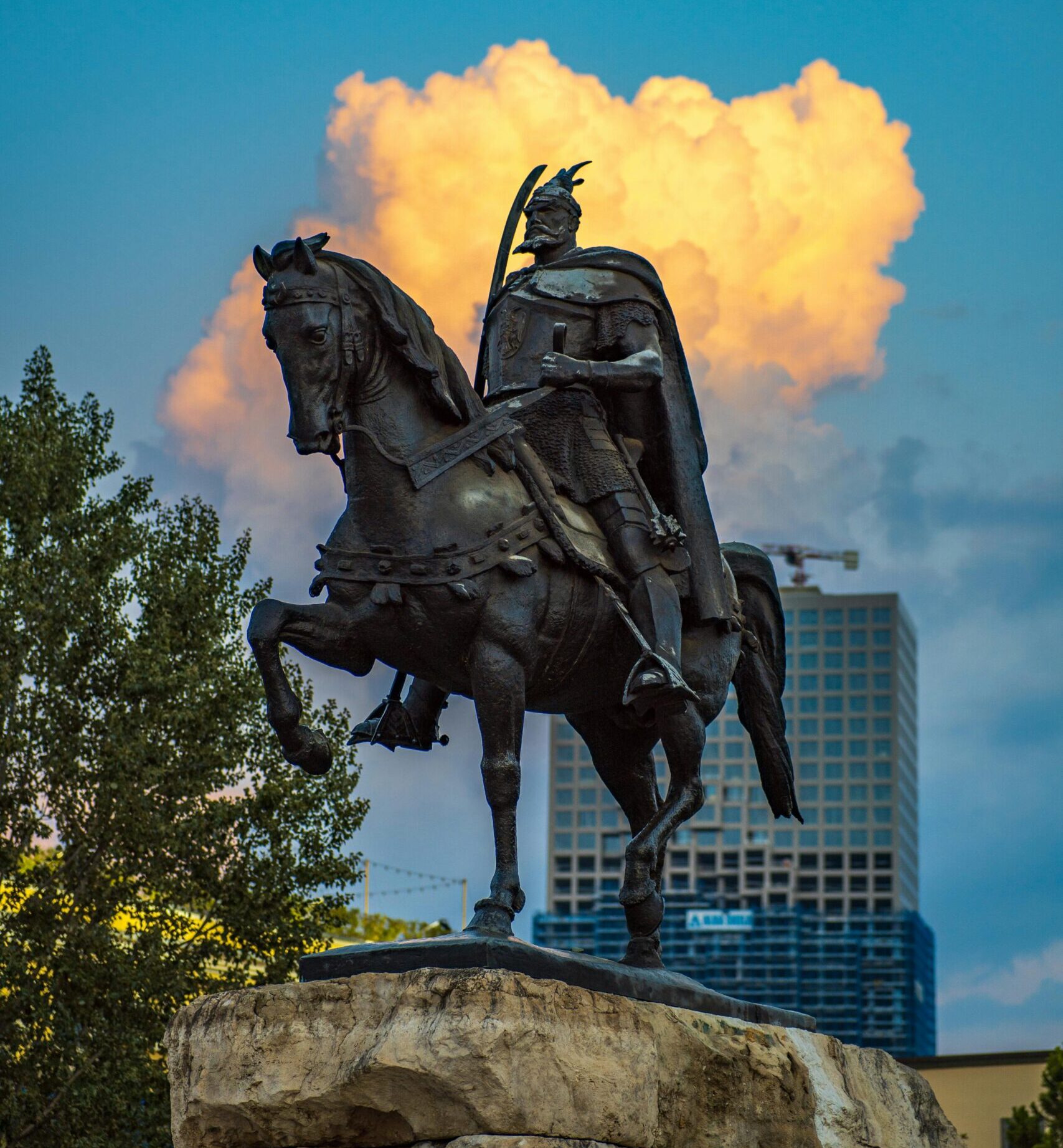 A dramatic equestrian statue silhouette set against a vivid sunset sky in Tirana, Albania.